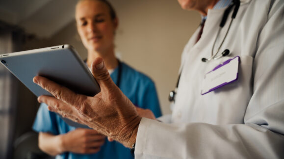 Close,Up,Of,Male,Doctor,Holding,Digital,Tablet,While,Female