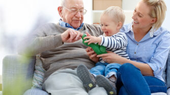 Portrait of senior man sitting with his daughter and grandson on sofa - Indoors
