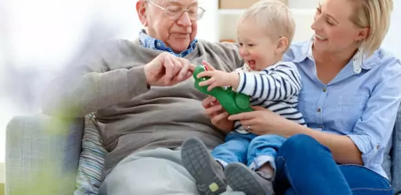 Portrait of senior man sitting with his daughter and grandson on sofa - Indoors